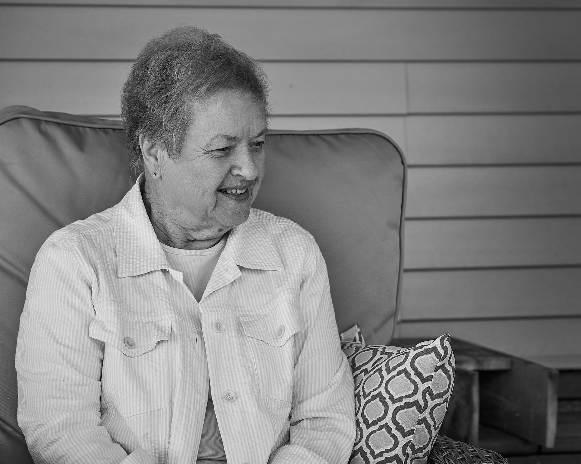 Black and white photo of my mom sitting in a chair looking off at a dog, I think.