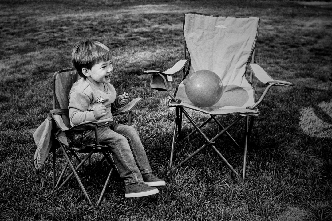 Black and white film photo of grandson in lawn chair