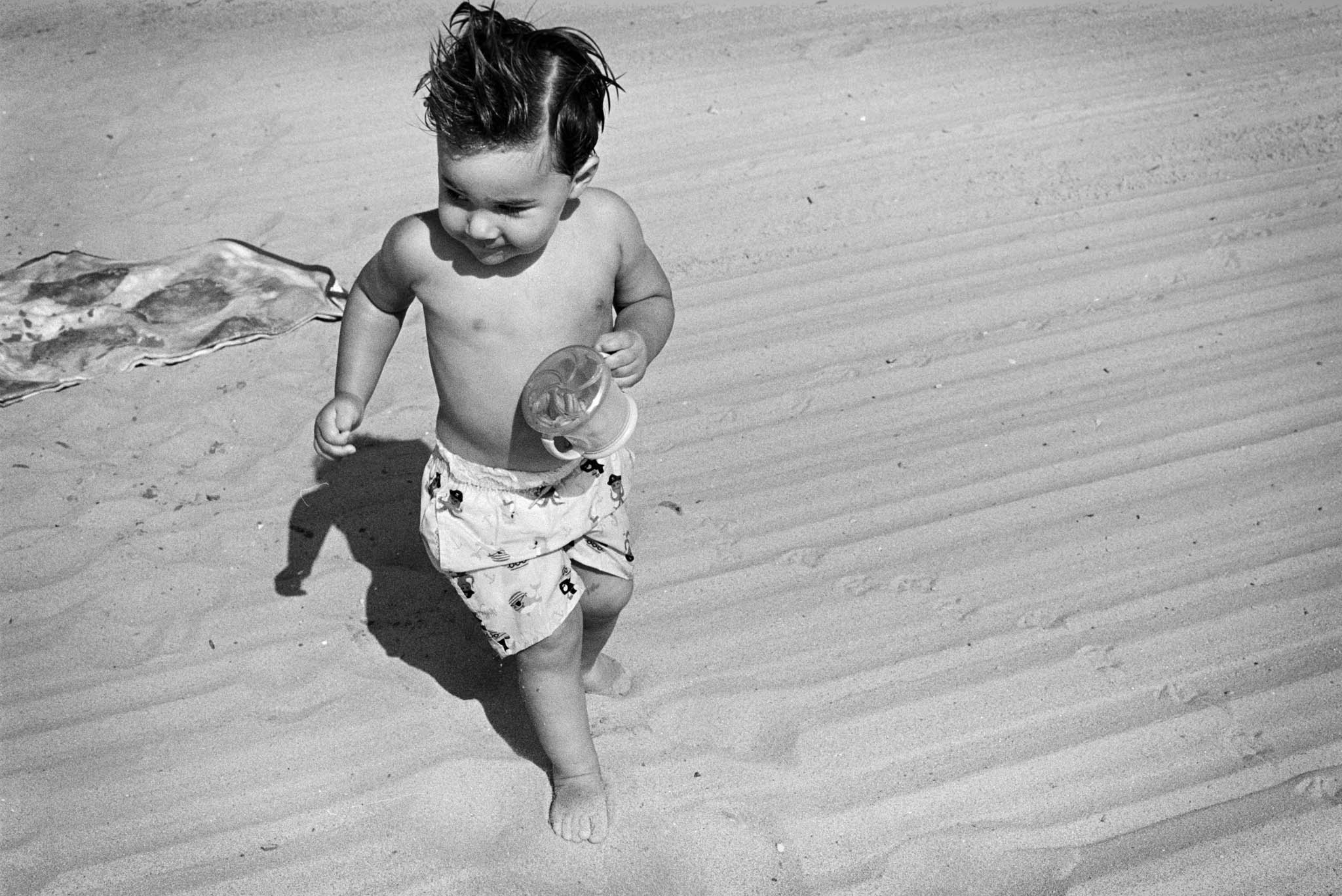 Black and white film photo of child running on beach