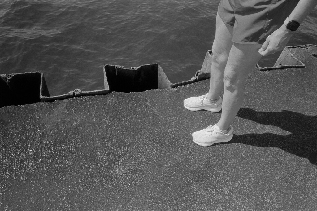 Black and white film photo of womans legs near water