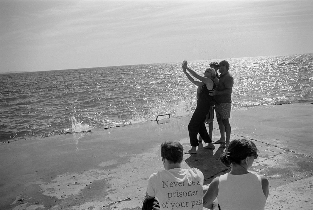 Black and white photo of people taking selfie on pier
