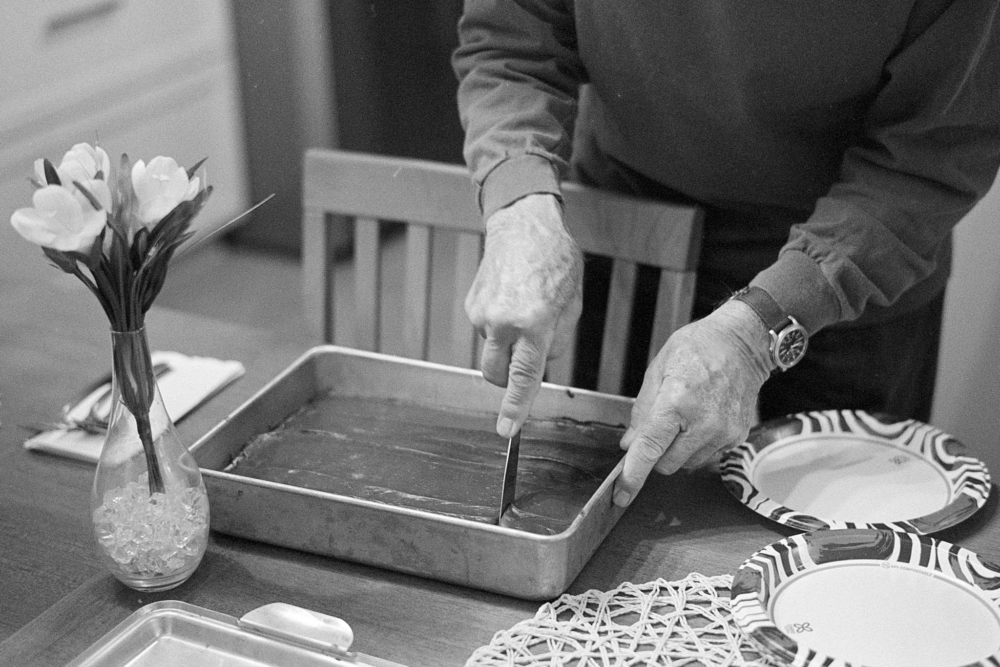 Black and white photo of man cutting birthday cake