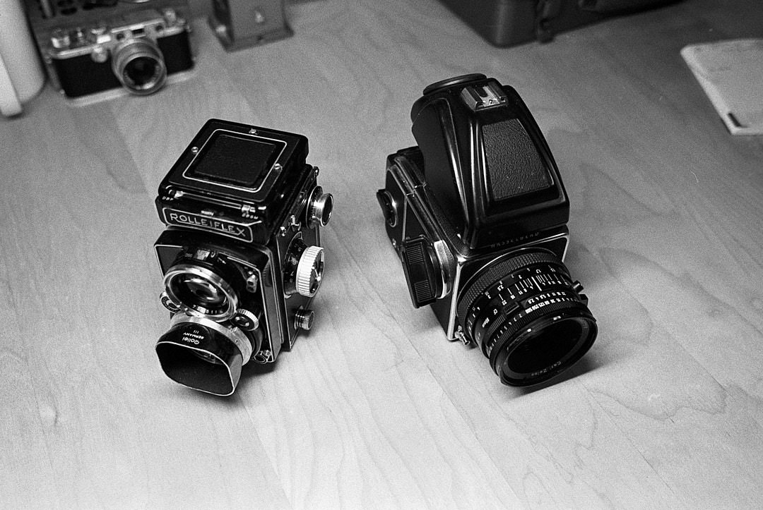 Black and white film photo of Rolleiflex and Hasselblad on desk