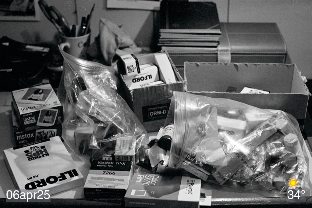 Black and white film photo of a bunch of film rolls