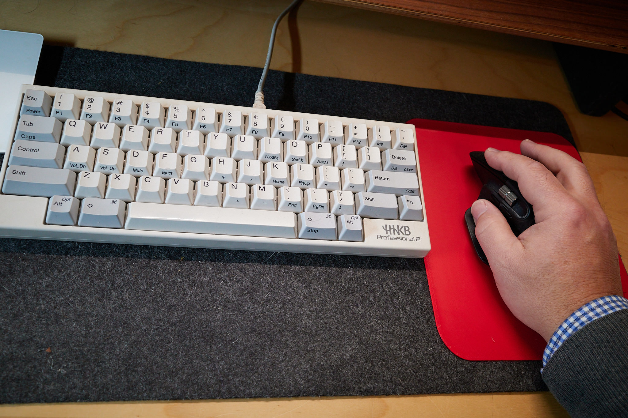 Photo of keyboard with a red mousepad next to it. My hand rests on the pad.