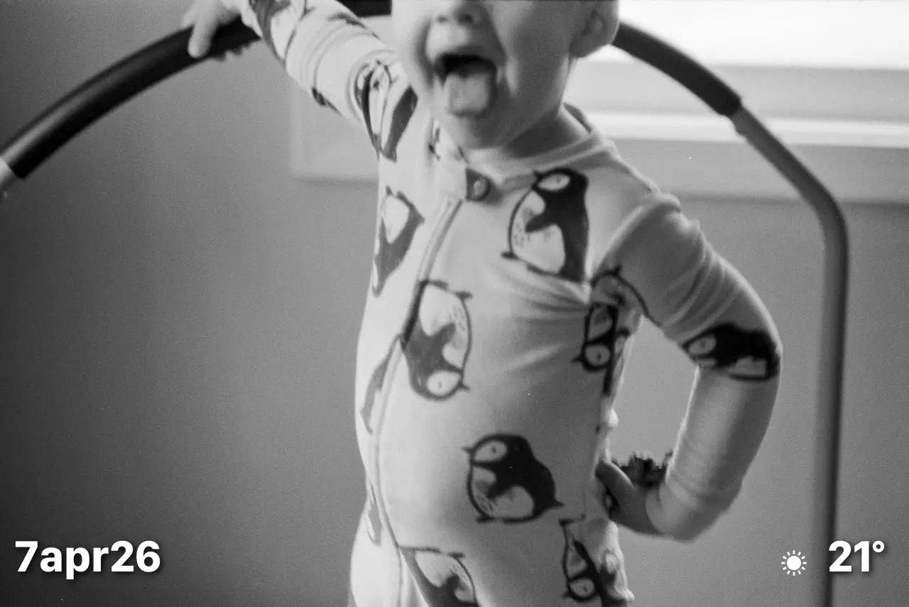 Black and white film photo of toddler sticking is tongue out