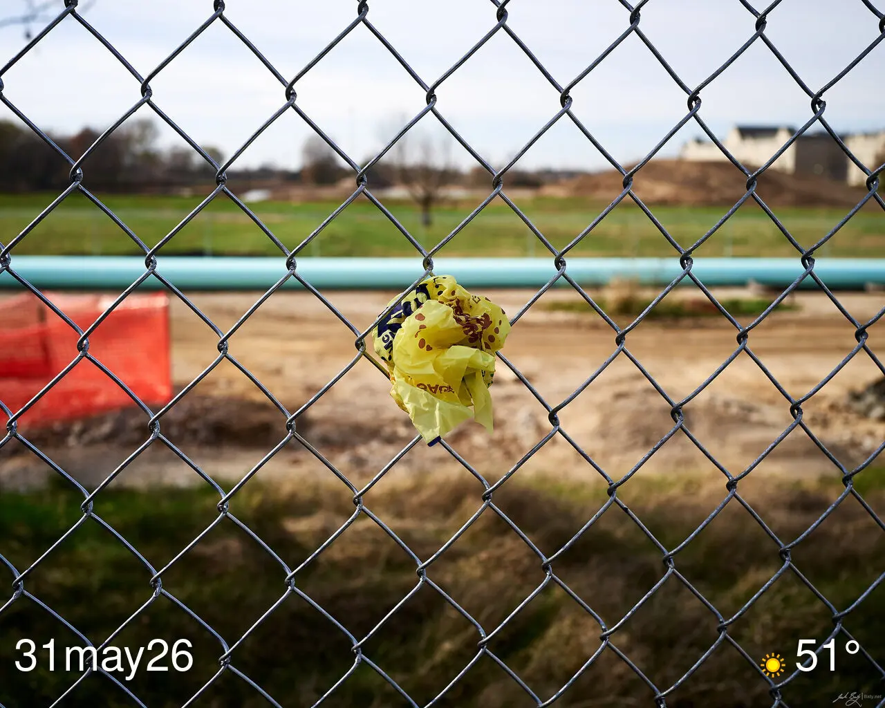 Fast food wrapper stuck in chain link fence