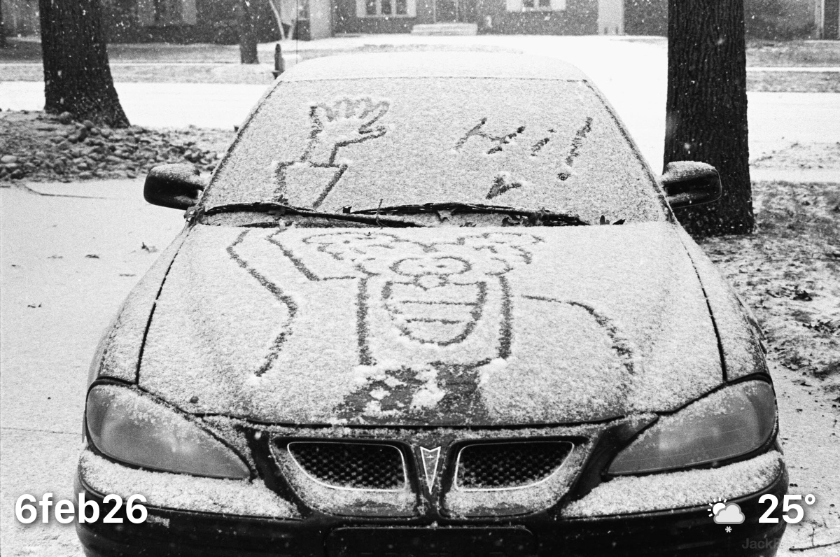 Car with Don Martin character saying Hi drawn in snow