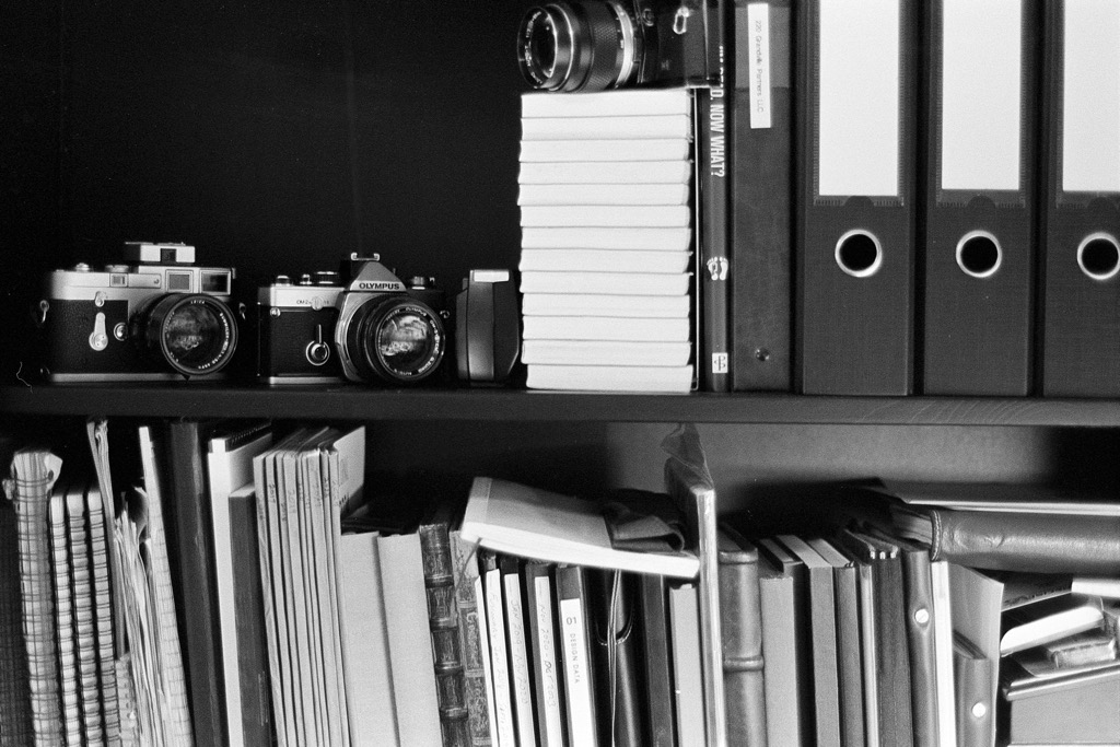 Black and white film photo of cameras and notebooks